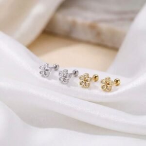 Silver flower stud earrings with clear teardrop crystals and screw back closures on a white velvet cloth