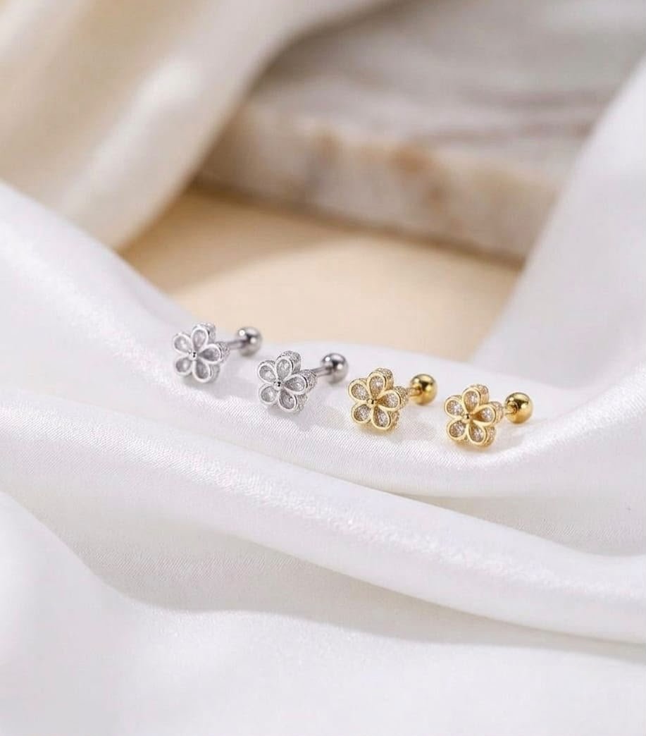 Silver flower stud earrings with clear teardrop crystals and screw back closures on a white velvet cloth
