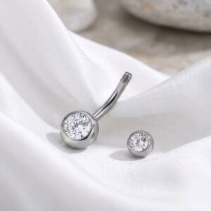 16G titanium belly button ring with clear bezel set crystals on white satin fabric